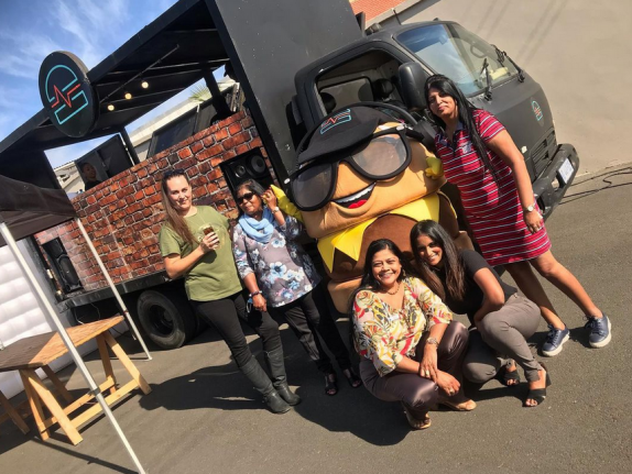 Group posing by a food truck with a hamburger mascot