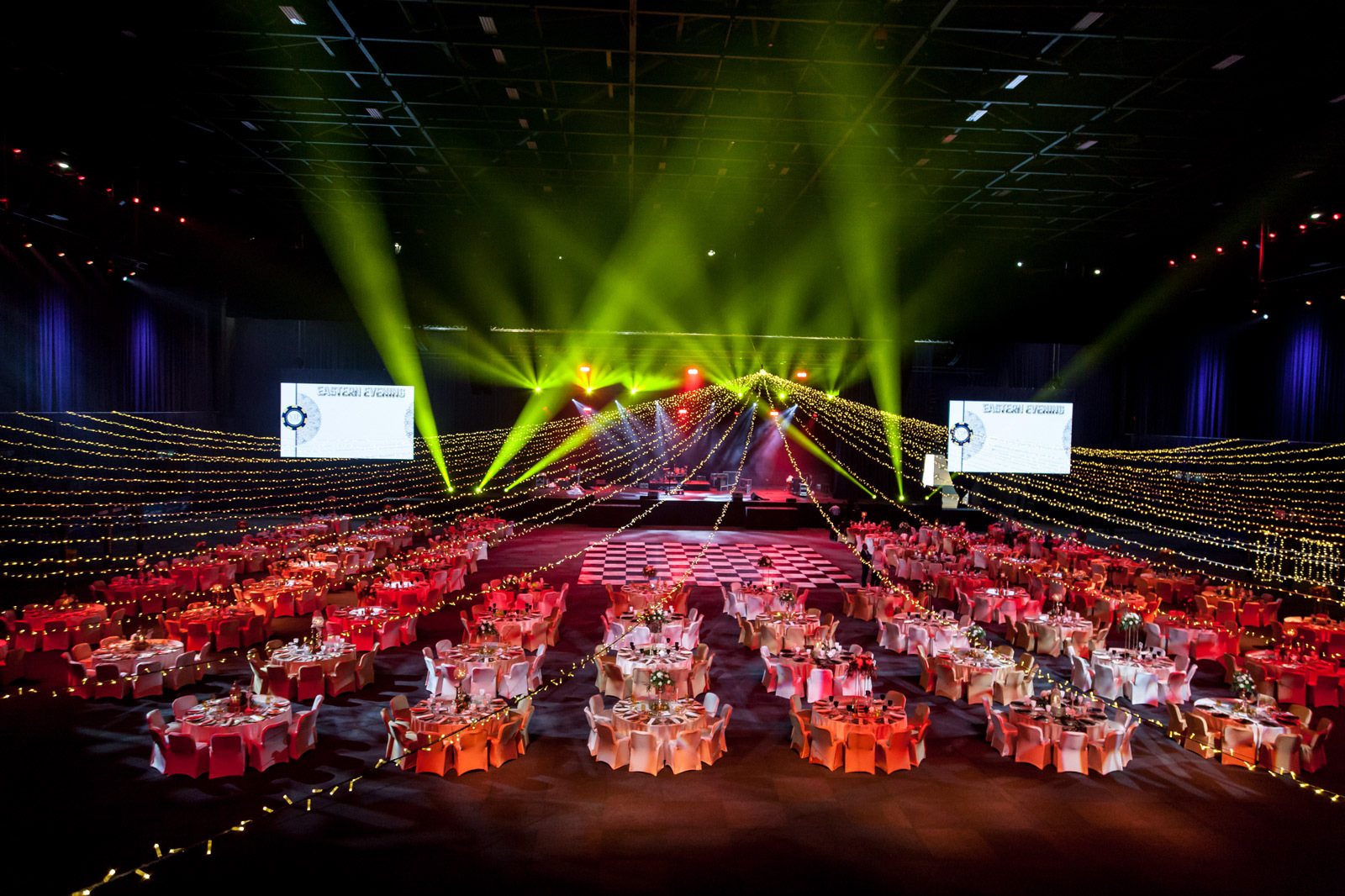 A spacious event hall with tables and colorful lighting.