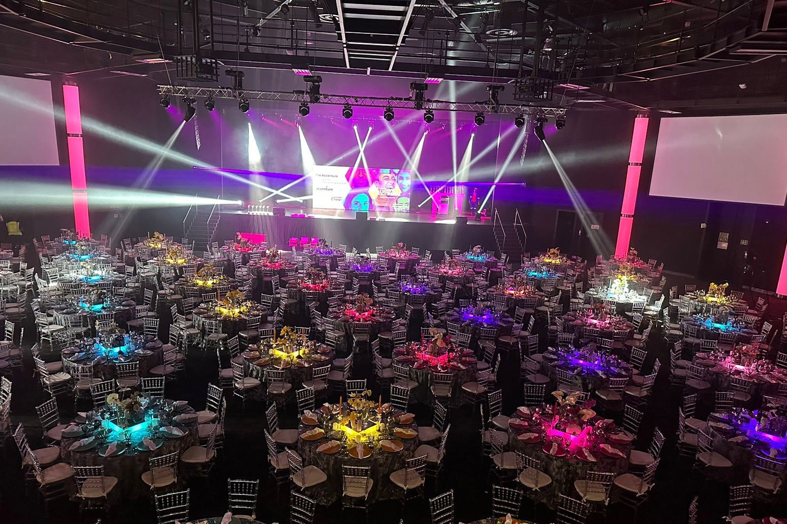 Large event space with tables and colorful lighting