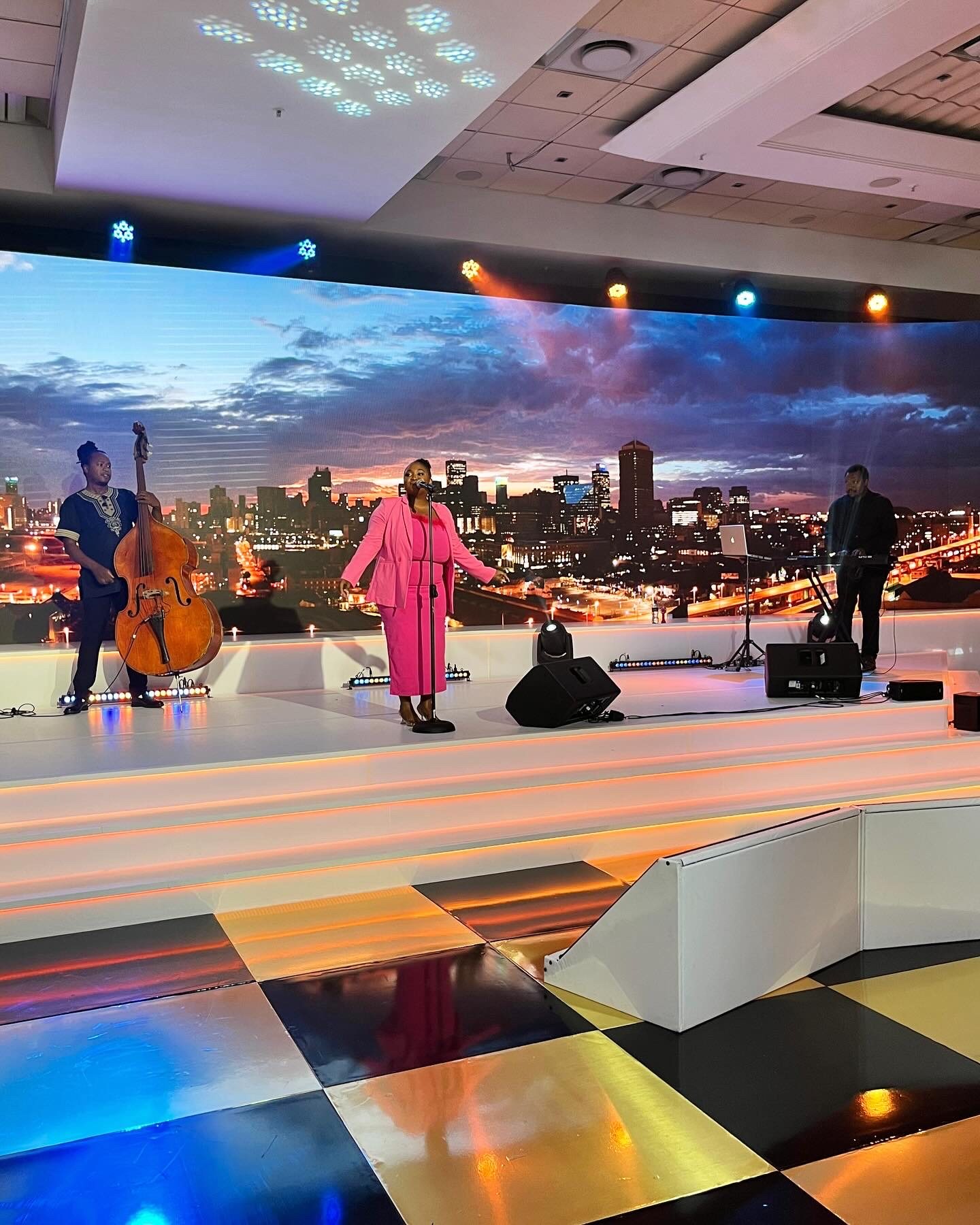Musicians performing on stage with a city skyline backdrop.