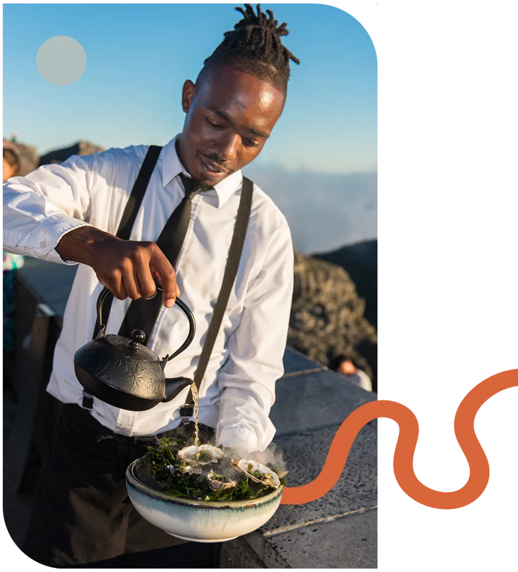 Waiter pouring tea into a decorative bowl outdoors