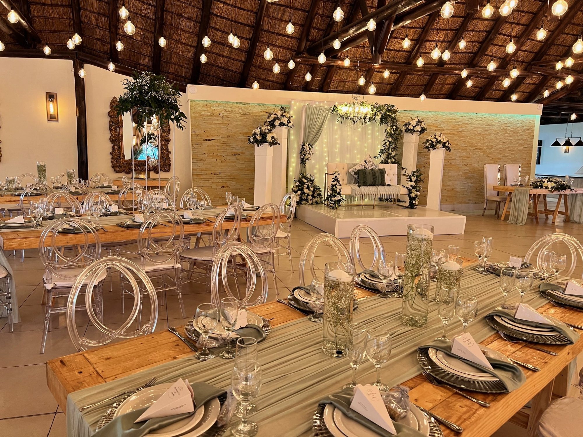 Elegant wedding reception setup with wooden tables and clear chairs.