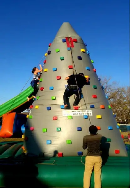 Inflatable climbing wall with colorful climbing holds and participants