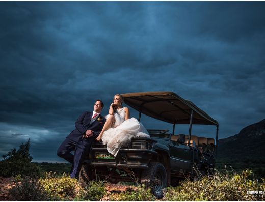 Bride and groom on safari vehicle with cloudy sky