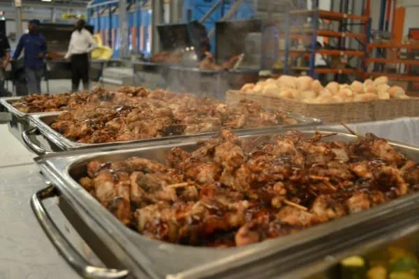 Trays of grilled meats and rolls on a buffet table.