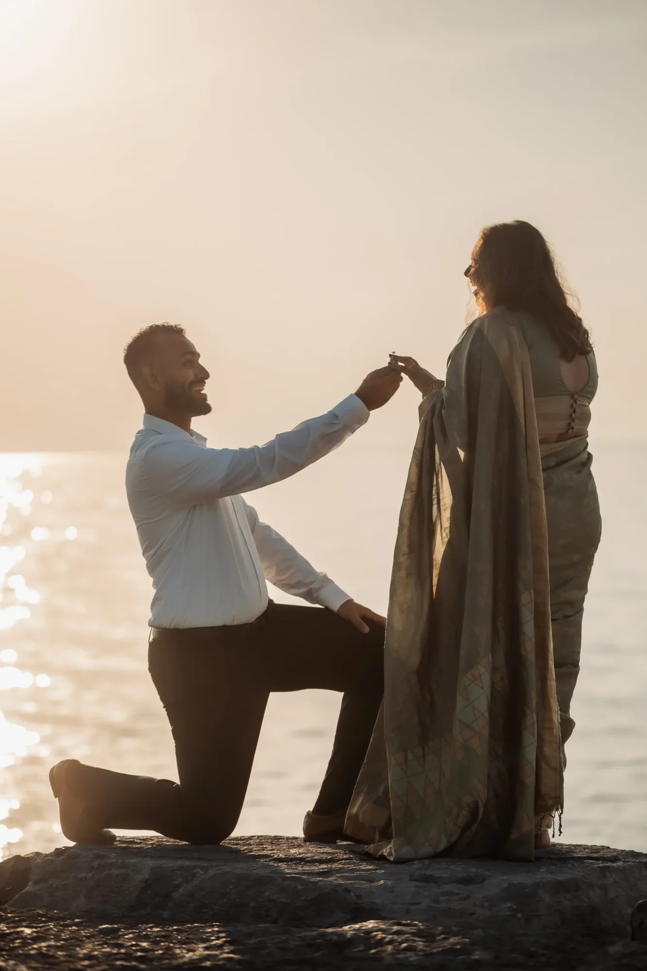 Man proposing to a woman at the beach during sunset