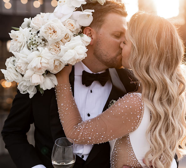 Couple kissing with a bouquet of white roses