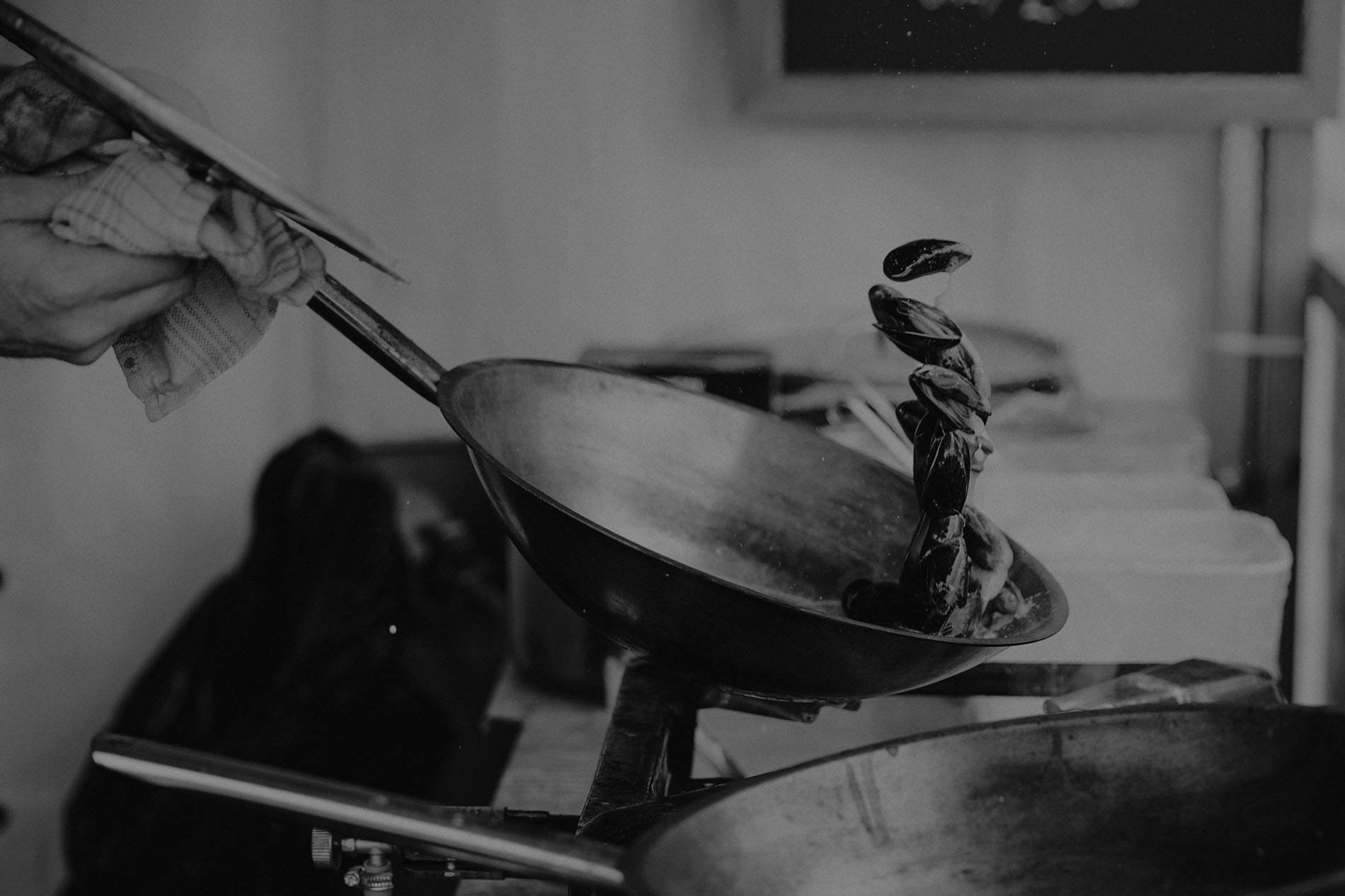 Chef holding a pan with mussels during cooking