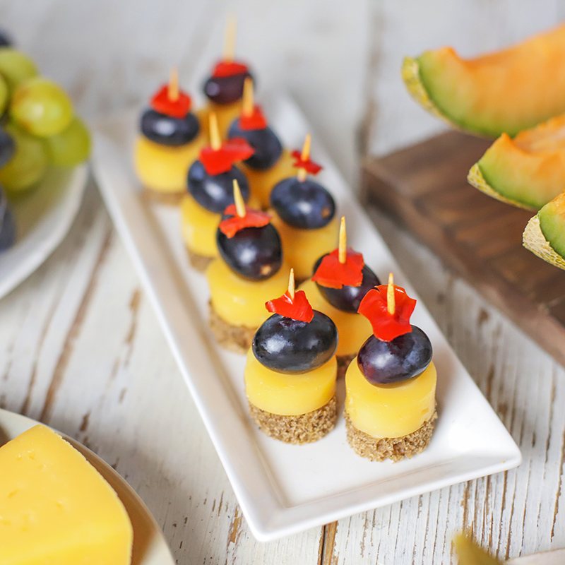 Mini dessert cups with blueberry and flower toppings on a platter.