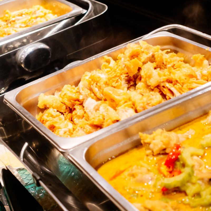 Three stainless steel trays with colorful buffet dishes