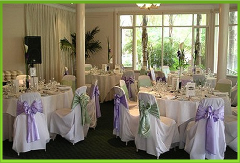Dining setup with white tablecloths and decorated chairs