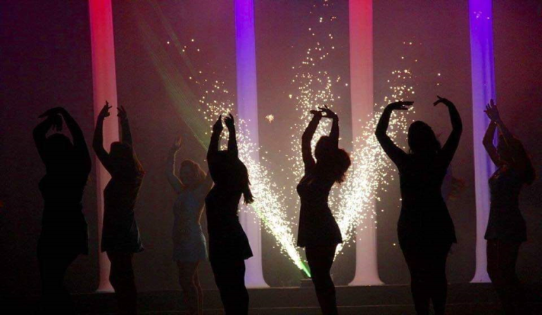 Silhouettes of performers with indoor fireworks display