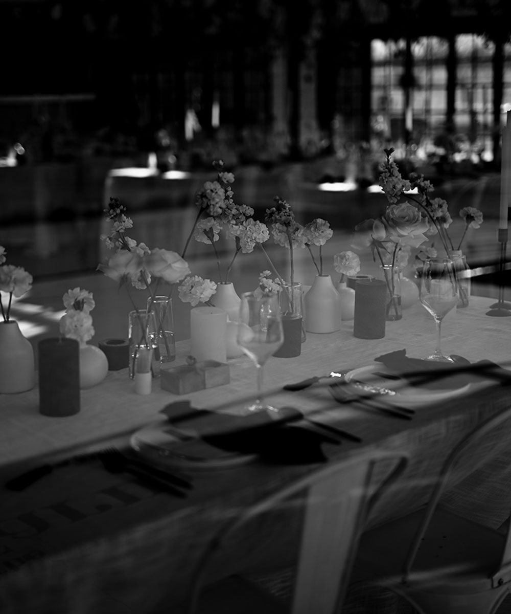 Black and white image of a styled table setting with flowers and glassware.